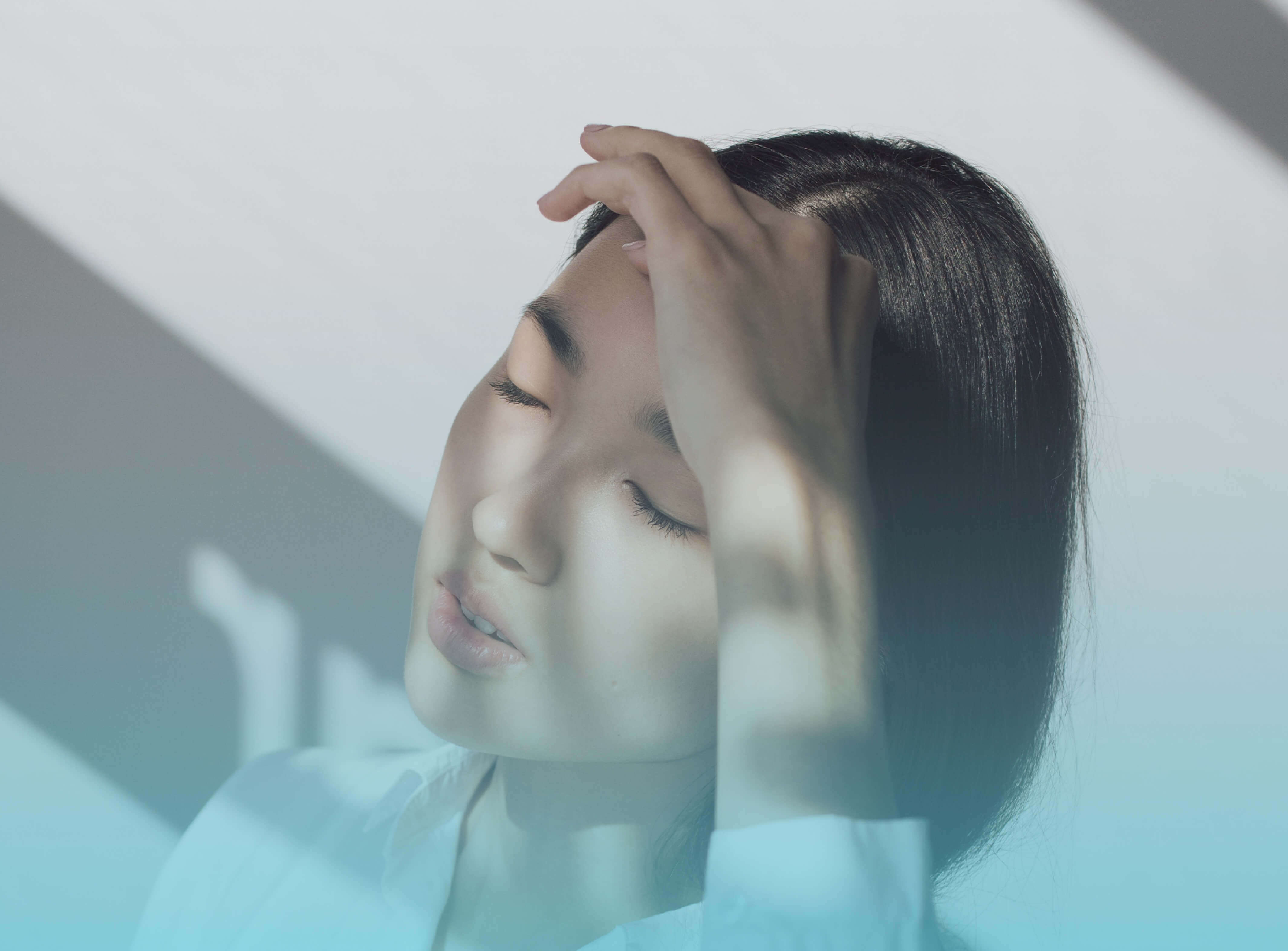 A woman with closed eyes on a light background.
